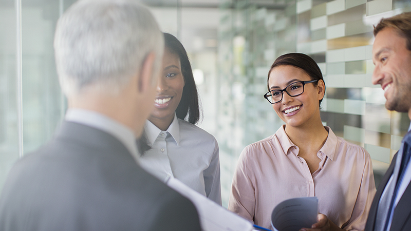 Business men and women exchanging greetings in office.