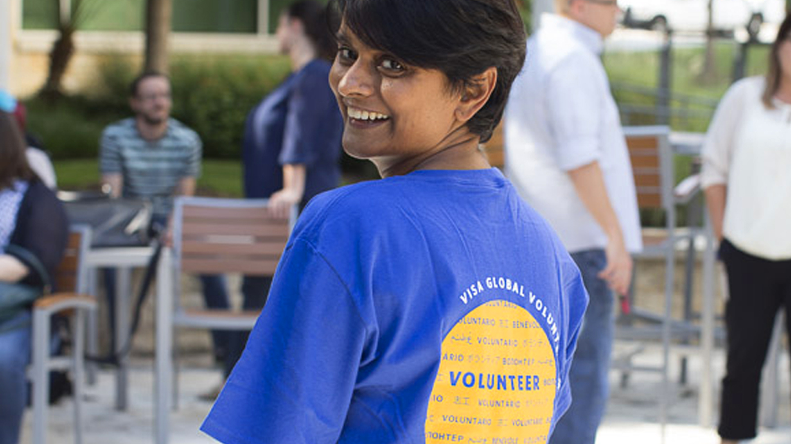 Visa volunteer smiling at camera with her back faced towards it. 